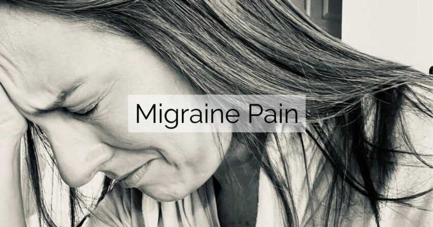 black and white image of woman holding head in pain from migraine headache